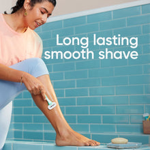 Women’s blue disposable razor with white head, held in hand for shaving