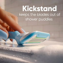 Manual razor with aqua handle resting on sink with foam, blades facing upward