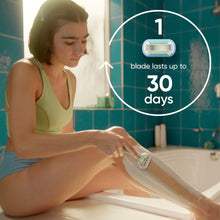Manual razor in use on leg, showing aqua razor handle with pivoting head