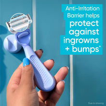 Hand holding a blue and purple Venus razor with exposed metal twin blade head.