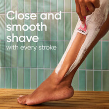 Disposable razor shaving a leg, with lather on skin and razor in hand