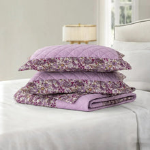 Quilt set stacked on bed: lilac floral comforter and coordinating pillow shams