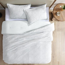 Light gray comforter set on bed with two shams and matching pillows