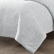 Light gray comforter close-up with textured woven fabric and draped edge
