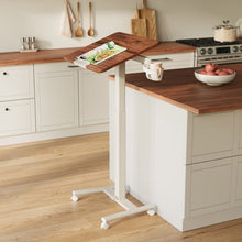 Versalift mobile desk tilted beside a kitchen counter, with a wood-grain top and caster wheels