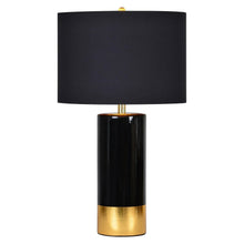 Black drum-shade table lamp with gold accent ring on glossy black base