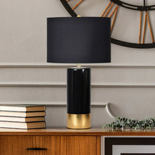 Black fabric shade table lamp with glossy black column and gold base ring