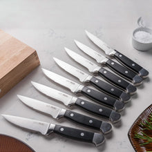 Steak knives with black handles and serrated edges, lined up