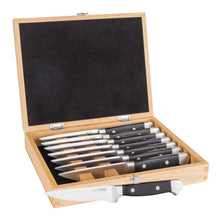Open wooden display box with serrated steak knife blades and black handles