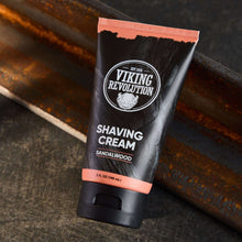 Shaving cream tube with orange cap and sandalwood label, on a dark wooden surface
