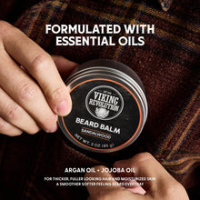 Beard balm tin in hand with sandalwood label on round metal jar