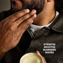 Beard balm application on a man's beard, small balm tin at bottom