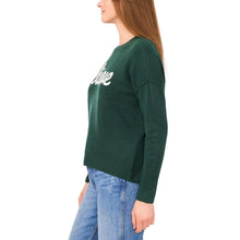 Green holiday sweater with 'Believe' graphic partly visible on sleeve