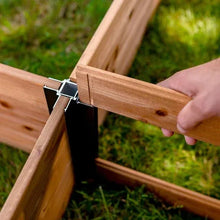 Raised garden bed corner connection with black metal bracket attached to wooden frame