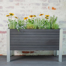 Front view of elevated garden planter with dark gray slats and mixed flowering plants