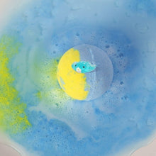 Blue bath water with a dissolving yellow-and-blue bath bomb and a tiny toy