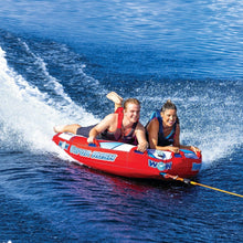 Two-person towable water tube with red and blue graphics; riders and yellow tow rope.