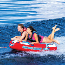 Two-person towable water tube with red and blue graphics; riders leaning back in waves.