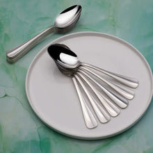Stainless dinner spoons with polished oval bowls and long handles arranged on a plate