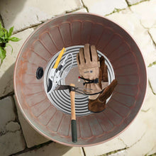 Garden water hose storage pot viewed from above with coiled hose and accessories inside