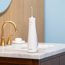 White cordless water flosser standing on bathroom countertop