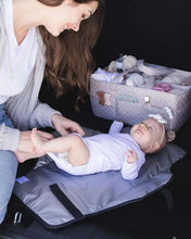 Quilted changing pad laid on a surface with a baby on top