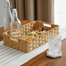 Rattan-style storage bin with woven handle, holding bottles and small items, tan