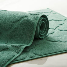 Rolled green geometric bath mat with textured fabric and curved edge