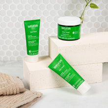 Weleda Skin Food set with green cream tubes and body butter jar near a towel.