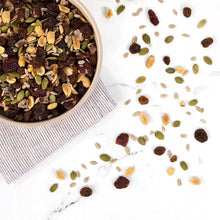 Trail mix pieces scattered from bowl: nuts, seeds, and dried fruit