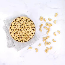 Raw cashews scattered around a bowl on a folded cloth