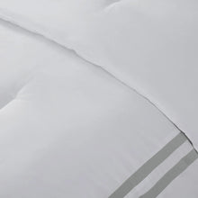 White bedding fabric with seam and gray striped trim band at the edge.