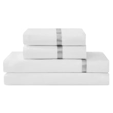 4-piece sheet set in white, neatly stacked flat and fitted sheets with ribbon trim