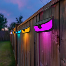 Solar wall lights on a wooden fence emitting purple and blue LED light