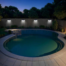 Solar LED motion-activated wall lights along a fence line by a swimming pool walkway