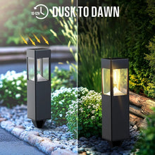 Two black solar path lights lit with warm glow outdoors