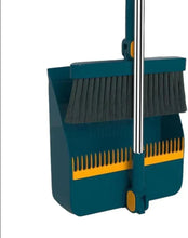 Blue upright dustpan with black broom bristles and yellow edge comb, metal handle