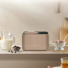 Taupe compact automatic ice cream maker on countertop with milk bottle and bowls