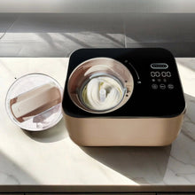 Taupe automatic ice cream maker with open mixing bowl and white churning paddle