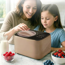 Taupe compact automatic ice cream maker with clear lid on table near berry bowls