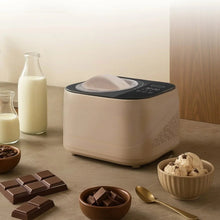 Taupe compact automatic ice cream maker with lid closed on countertop beside bowls