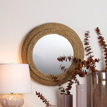 Round seagrass wall mirror with woven natural fiber frame and circular glass center.