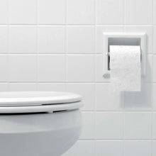 White bath tissue sheets in dispenser beside a toilet bowl.