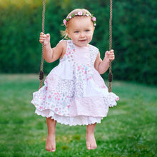 Toddler on wooden swing seat with braided ropes and black connector bands