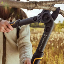 Hand holding dark blue lopper with yellow accents for pruning branches