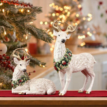 Pair of deer figurines: one lying, one standing, both with green berry wreaths.