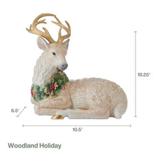 Resting deer figurine with long antlers and a green holly berry wreath in front.