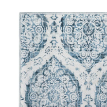 Indoor area rug pattern close-up with light blue damask-style motifs on white background