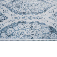 Close-up of indoor area rug showing light blue floral medallion pattern on white