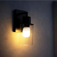 Wall-mounted bulb cam light with frosted globe emitting warm light and front camera lens